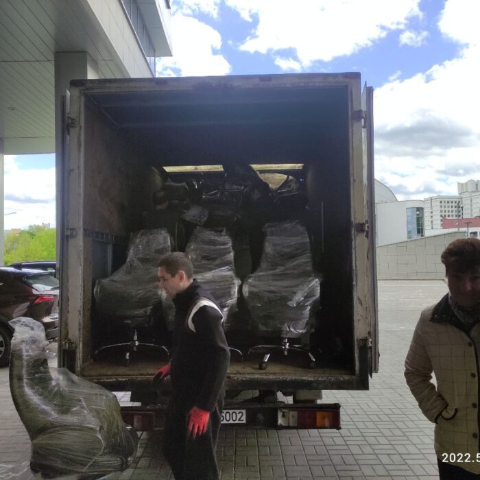 Загрузка упакованных офисных стульев в кузов грузовика для дальнейшей перевозки